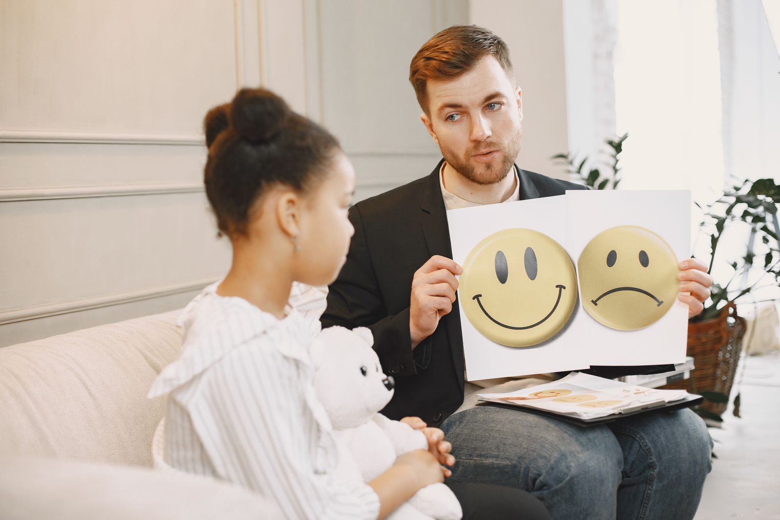 A therapist using emotion cards to help a child express her feelings